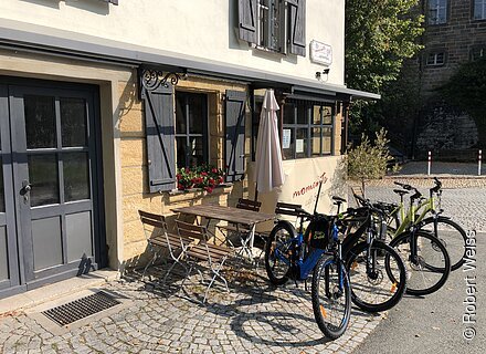 Ein Gasthaus mit Gelegenheiten, draußen zu sitzen, davor einige Fahrräder