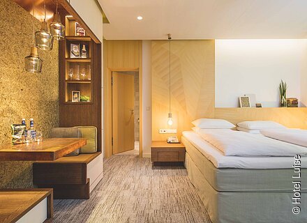 Ein Doppelzimmer in warmen Licht mit holzlastigen Interieur.