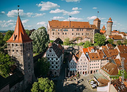 Blick auf eine mächtige Burganlage, umgeben von mittelalterlichen Häusern und Türmen