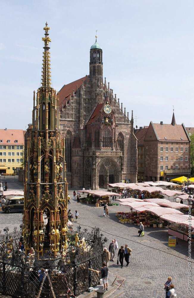 Blick über den Hauptmarkt mit dem Schönen Brunnen, der Frauenkirche und dem traditionsreichen Wochenmarkt mit seinen Obst-, Gemüse- und Blumenhändlern.