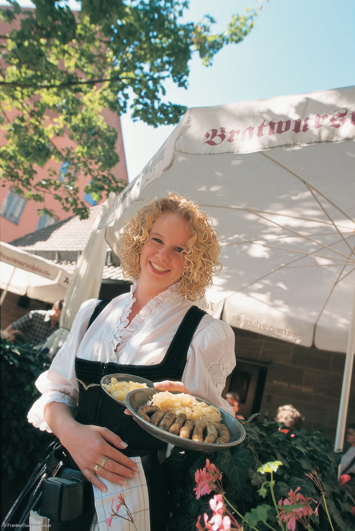 "Bratwursthäusle", Kellnerin Yvette Becher mit Bratwürsten auf Kraut